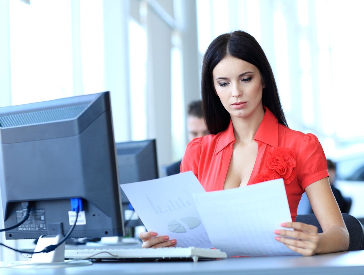young business woman reading sitting at the desk on office background 